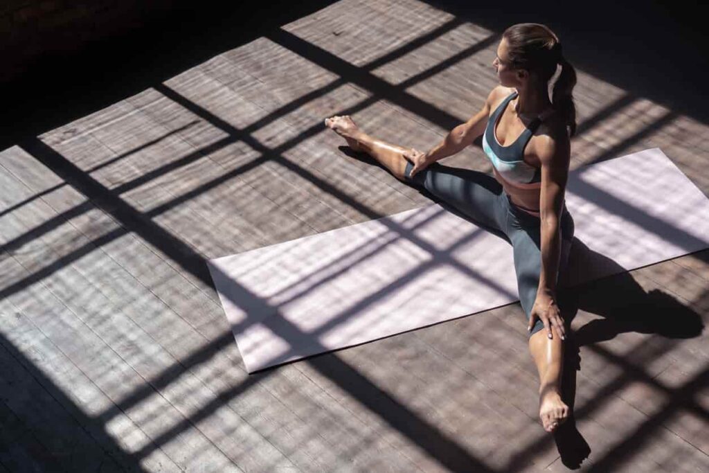 femme sur tapis de gym en train de faire un exercice souplesse danse